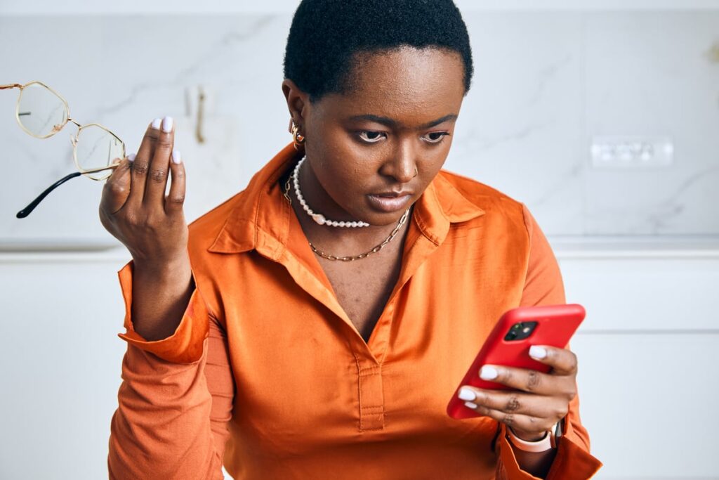 XRP Is Down 54% in 6 Months. Has It Become a Bargain Buy? A person with a disappointed expression looking at their smartphone.