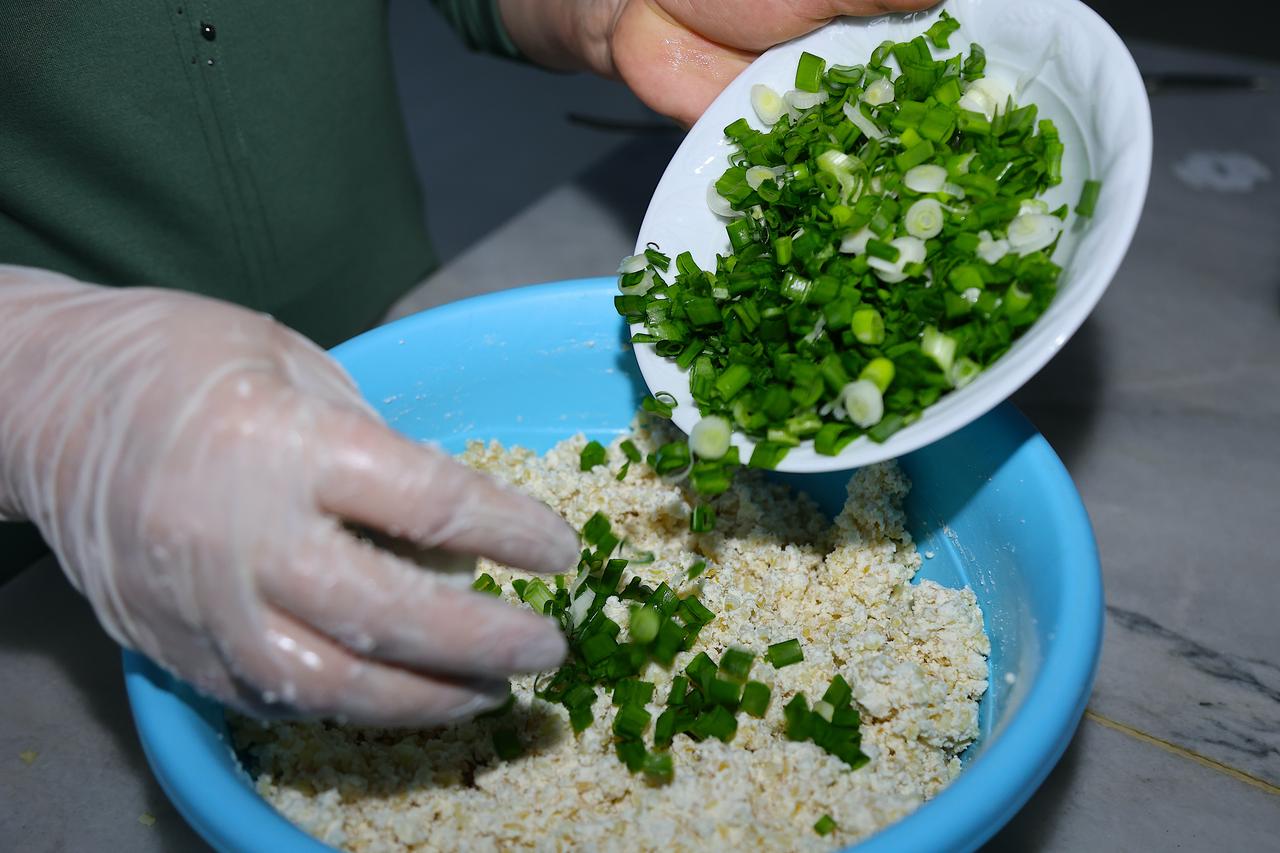 Chopped green onions are added to a mixture of lor cheese and bulgur while preparing the filling for lor dolmasi in Bayburt, Türkiye, March 14, 2026. (AA Photo)