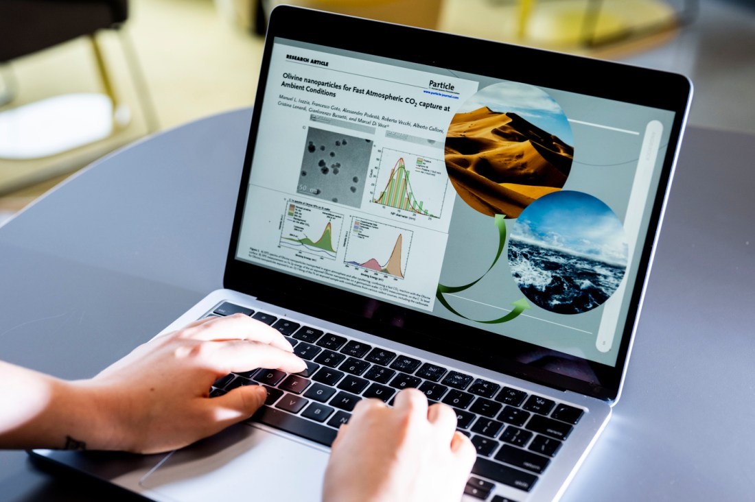 Close up of Jenna Woods' hands typing on a laptop. The screen is open to a slide with various images and infographics on it. 