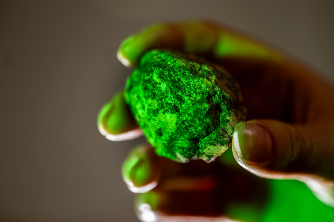 Close up of Jenna Woods hand holding a rock lit by green lighting. 