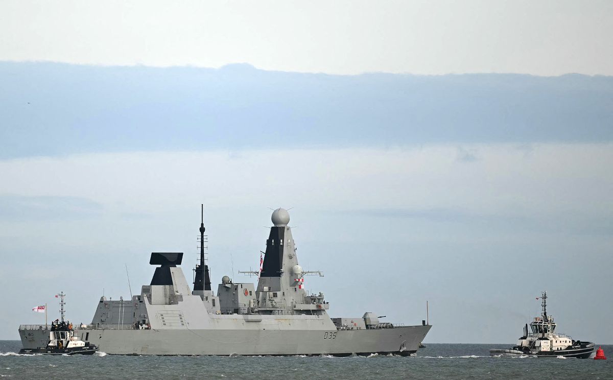 HMS Dragon being guided by tug boat