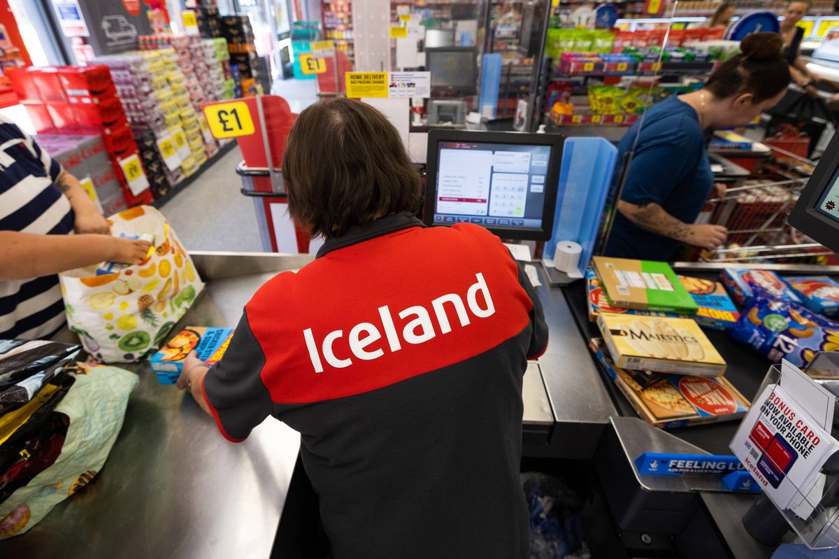 An employee serves customers at an Iceland Foods Ltd. supermarket in Christchurch, UK, on Wednesday, June 15, 2022. "Britain's cost-of-living crisis -- on track to big the biggest squeeze since the mid-70s -- will continue to worsen before it starts to ease at some point next year," said Jack Leslie, senior economist at the Resolution Foundation, a research group campaigning against poverty.