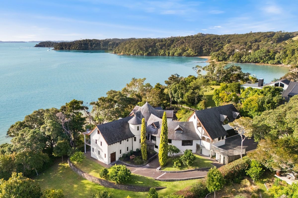 Aerial view of white-washed house next to the water in New Zealand in the Bay of Islands for sale design based on Castell Coch and called Castell Bach with agent Mackys Real Estate part of Bayleys Realty Group for over $3m New Zealand dollars