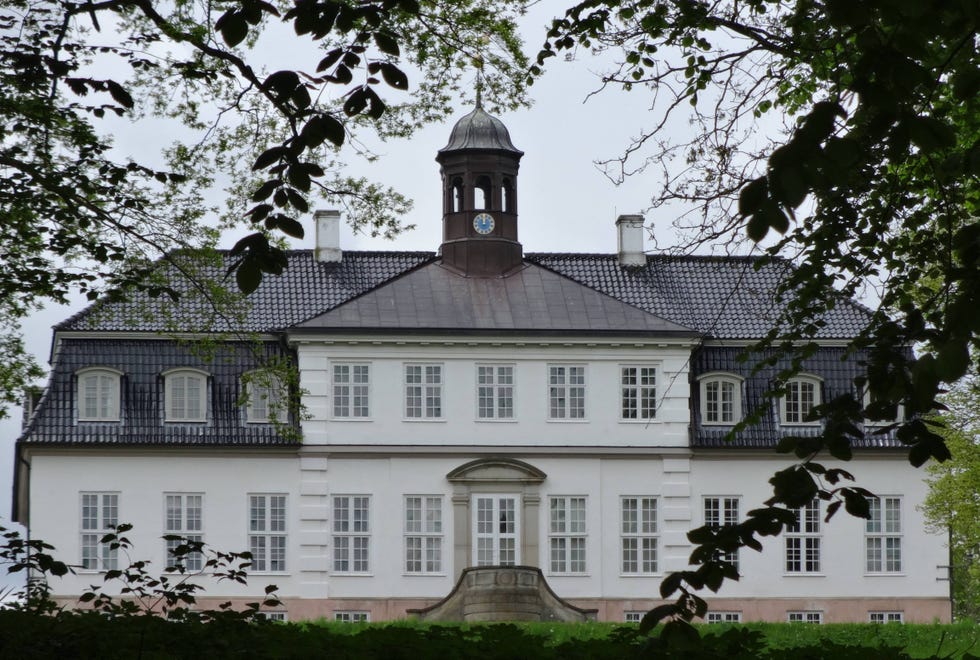Historic building with a clock tower surrounded by trees.