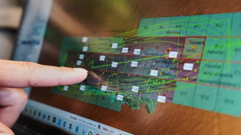 An archaeologist points to a computer screen, showing a map...