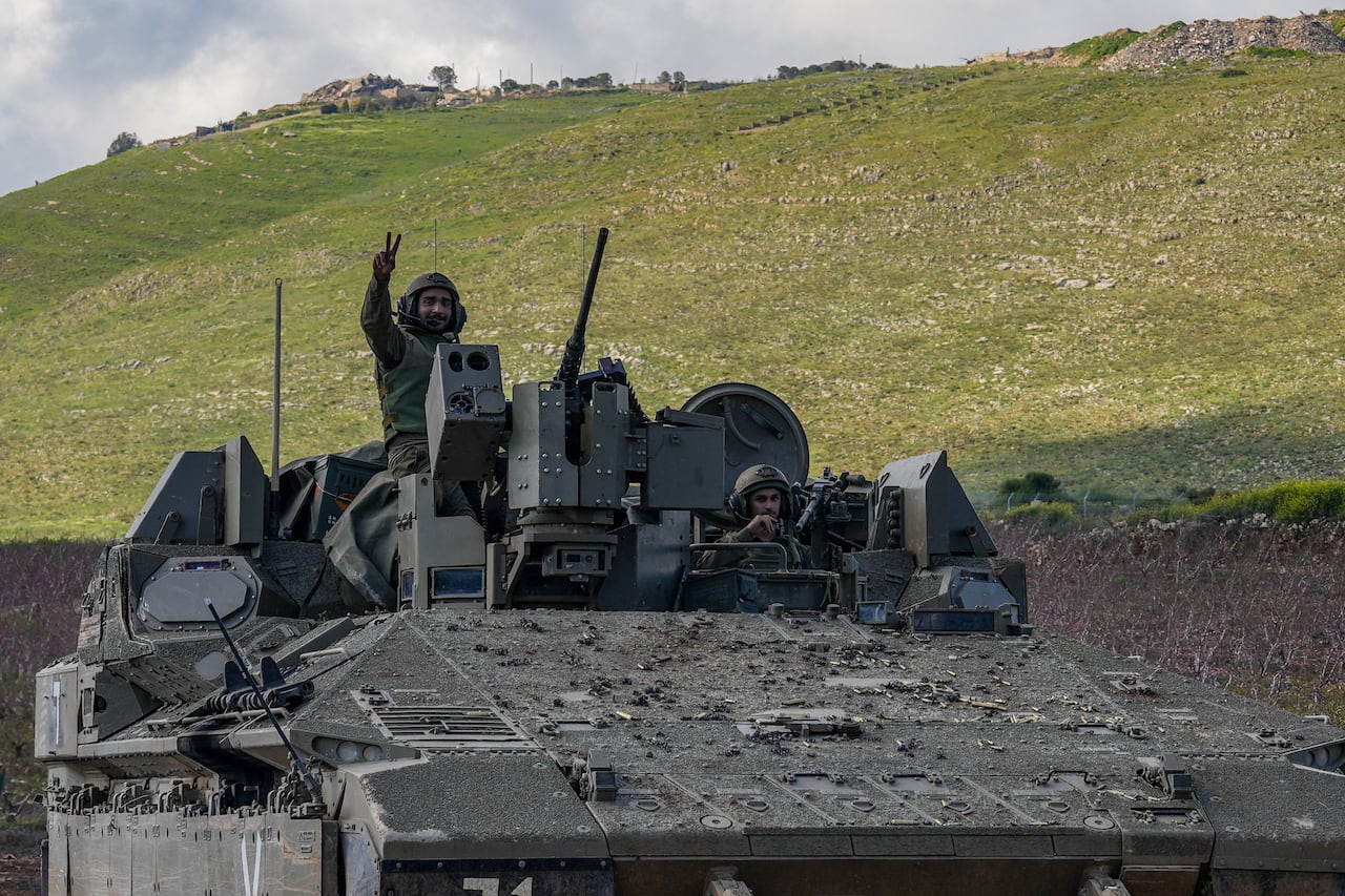 An Israeli soldier gestures from an Israeli armoured personnel carrier (APC), as they leave southern Lebanon and enter Israel, as seen from the Israeli side of the border, April 8, 2026.