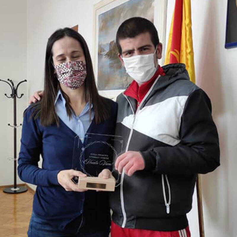 A young woman standing next to a young boy holding an award.