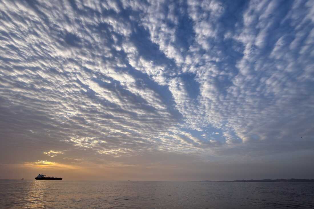 The sun rises behind a tanker anchored in the Strait of Hormuz off the coast of Qeshm Island, Iran, Saturday, April 18, 2026. 