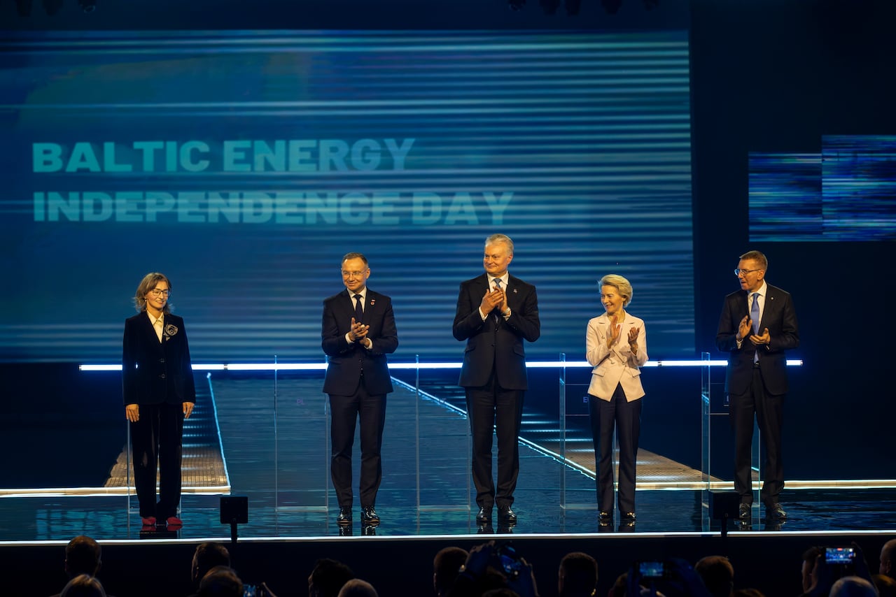 People in suits stand on a stage.
