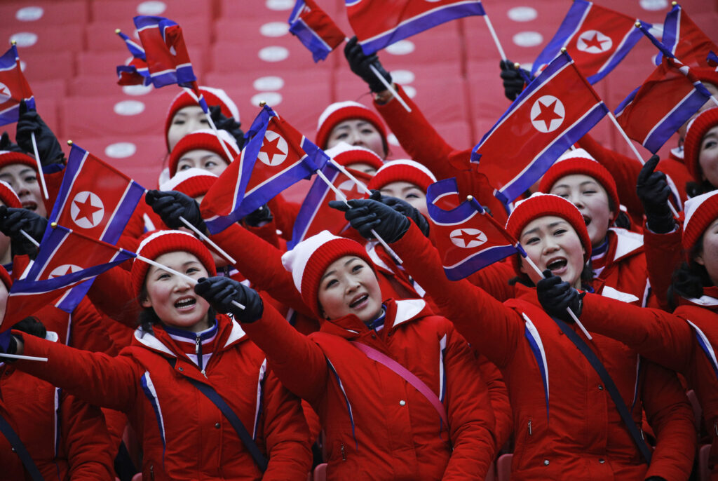 Members of the North Korean delegation wave flags at the women
