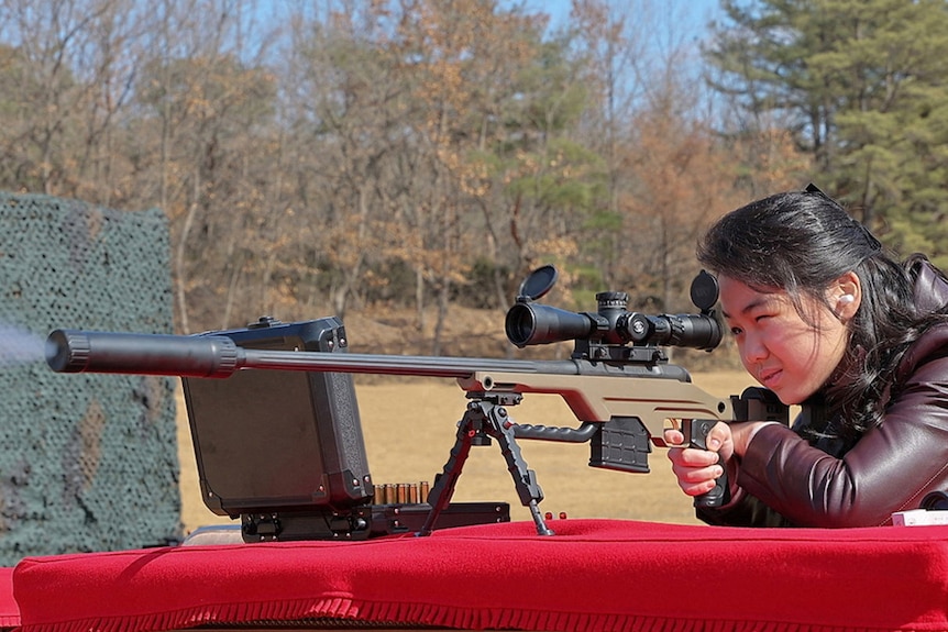 A woman looks through the view finder on a gun.