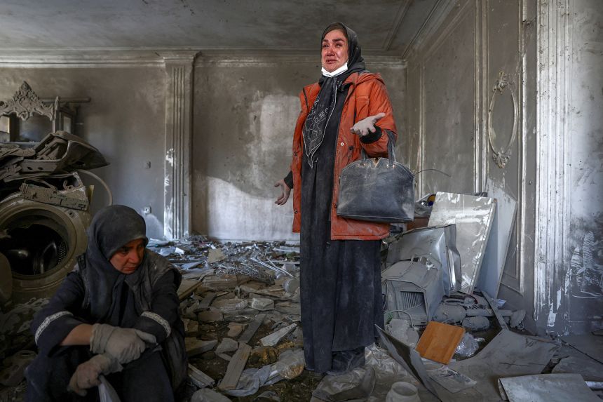 A woman stands in her brother's home which was damaged by an airstrike strike in Tehran, Iran, on Monday.