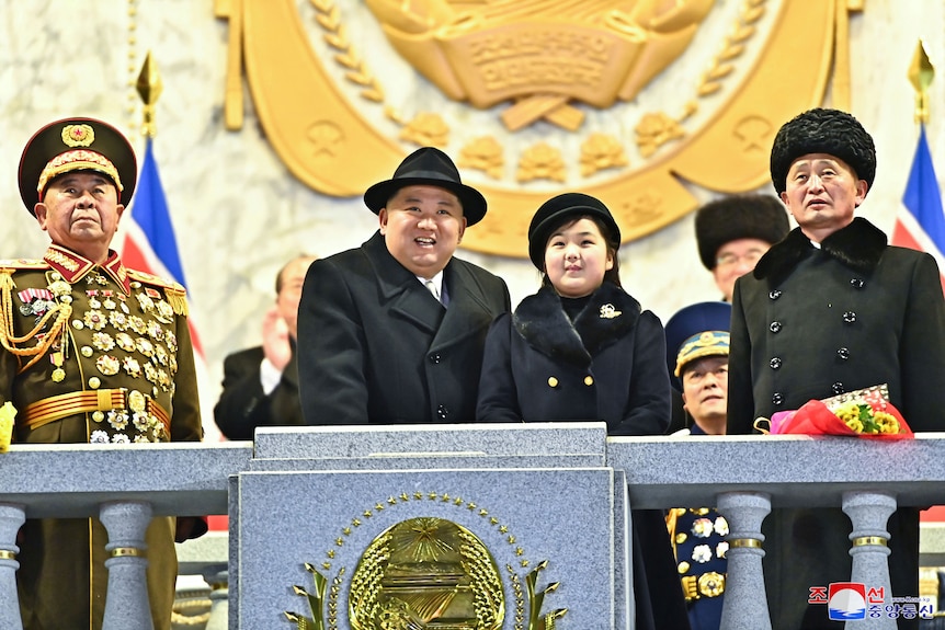 A man and girl stand next to each other smiling on a balcony.