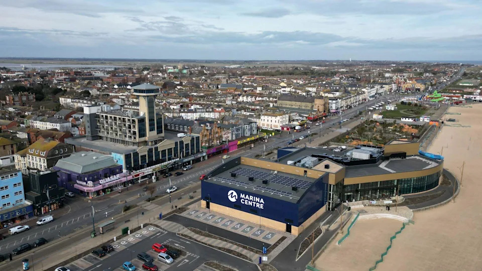 A drone shot of Marine Parade in Great Yarmouth looking north along the beach, with a tower, leisure centre and seafront arcades in view on a cloudy day