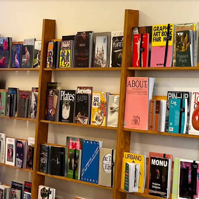 Display of various magazines on wooden shelves in a shop.