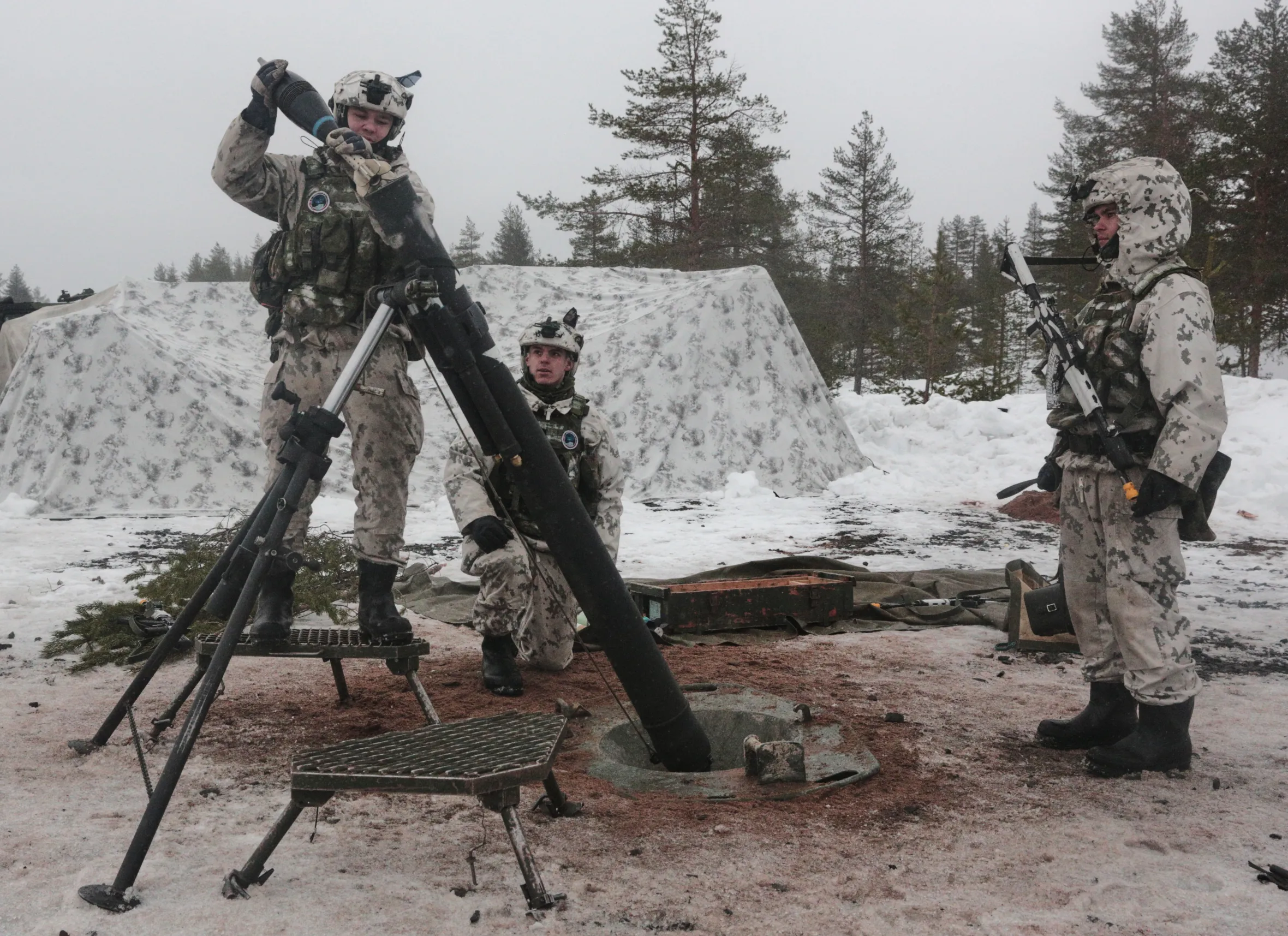 Finnish soldiers load a heavy mortar during NATO arctic exercises.