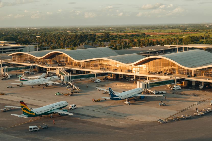 Airplanes at modern airport terminal with wave-shaped roof.