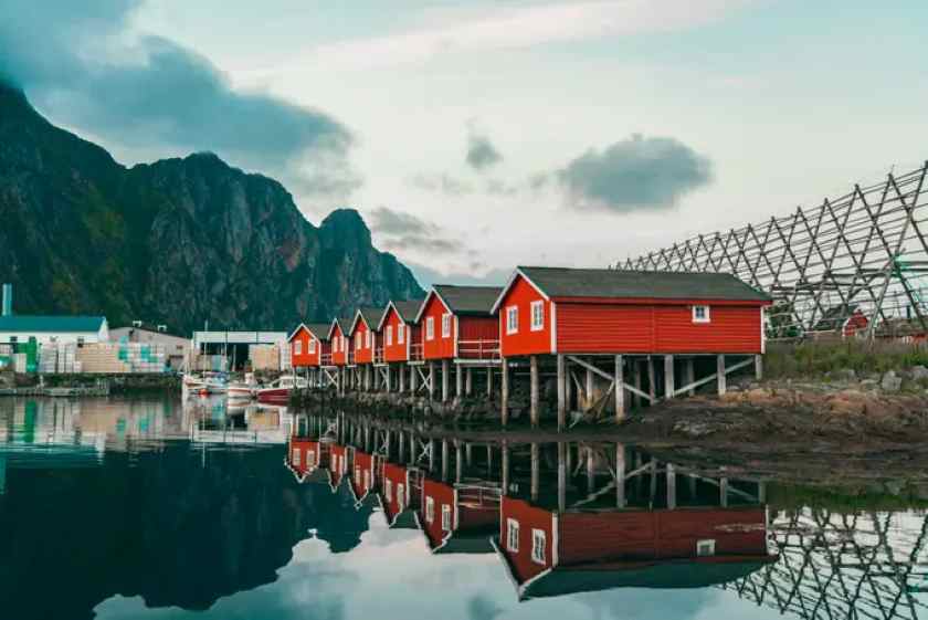 Red wooden houses on stilts by the water in norway.