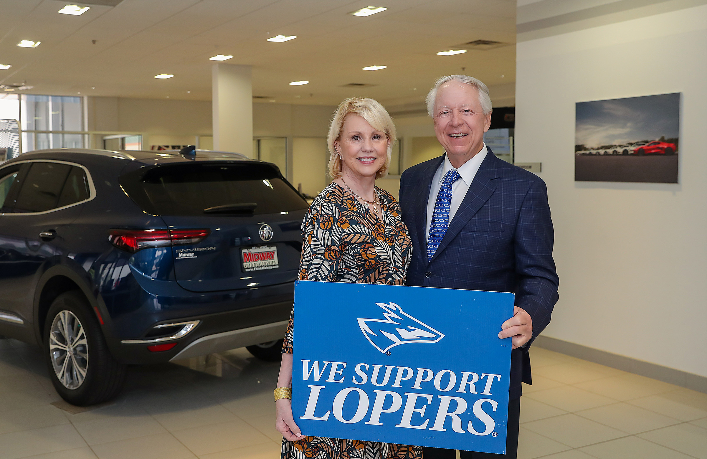 Carey and Brian Hamilton are pictured inside a local Midway automotive dealership, holding a UNK sign.