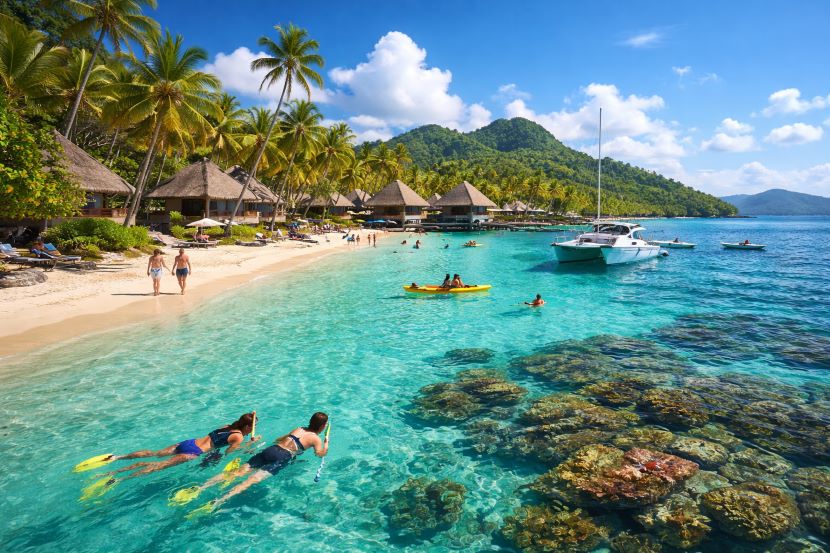 Beautiful fiji beach with clear turquoise water, palm trees, and boats.