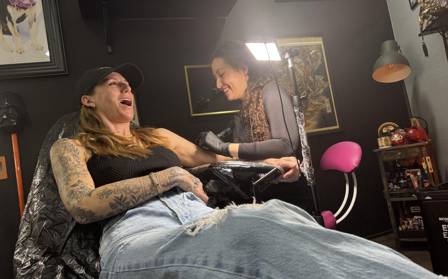 Jenn and Anastasia laughing while sitting together in the tattoo studio