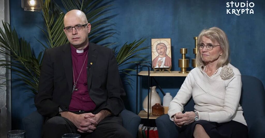 Finland Convicts Christian MP and Bishop Over Biblical Marriage Pamphlet Lutheran Bishop Juhana Pohjola and Member of Parliament Dr. Paivi Rasanen speak with Studio Krypta, a studio interview setting with a blue backdrop, a small icon of Jesus, and the Studio Krypta logo.