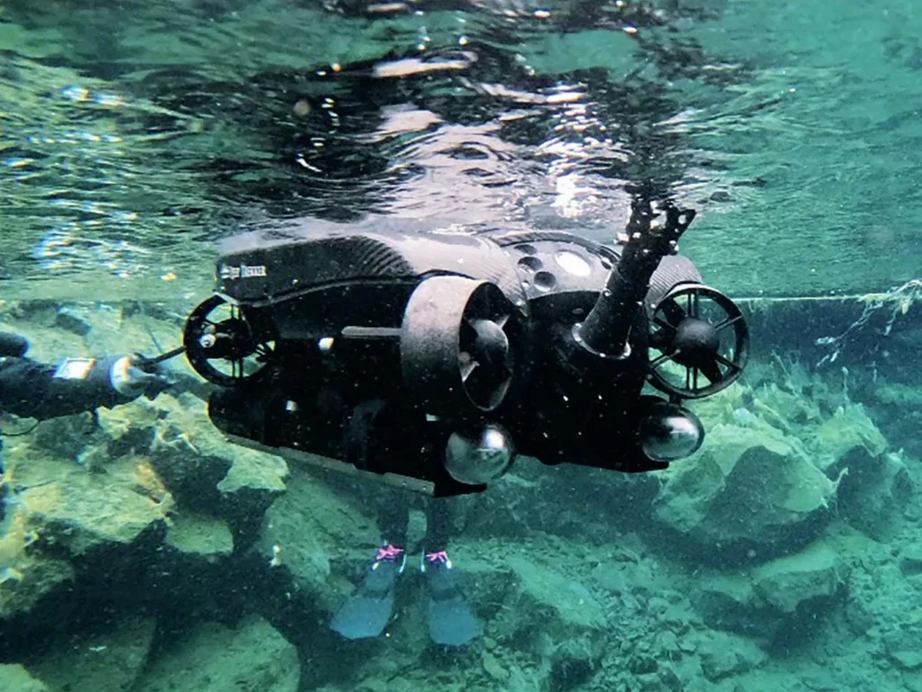 A Deep Trekker ROV being deployed in the Silfra Hellir headpool for underwater exploration.