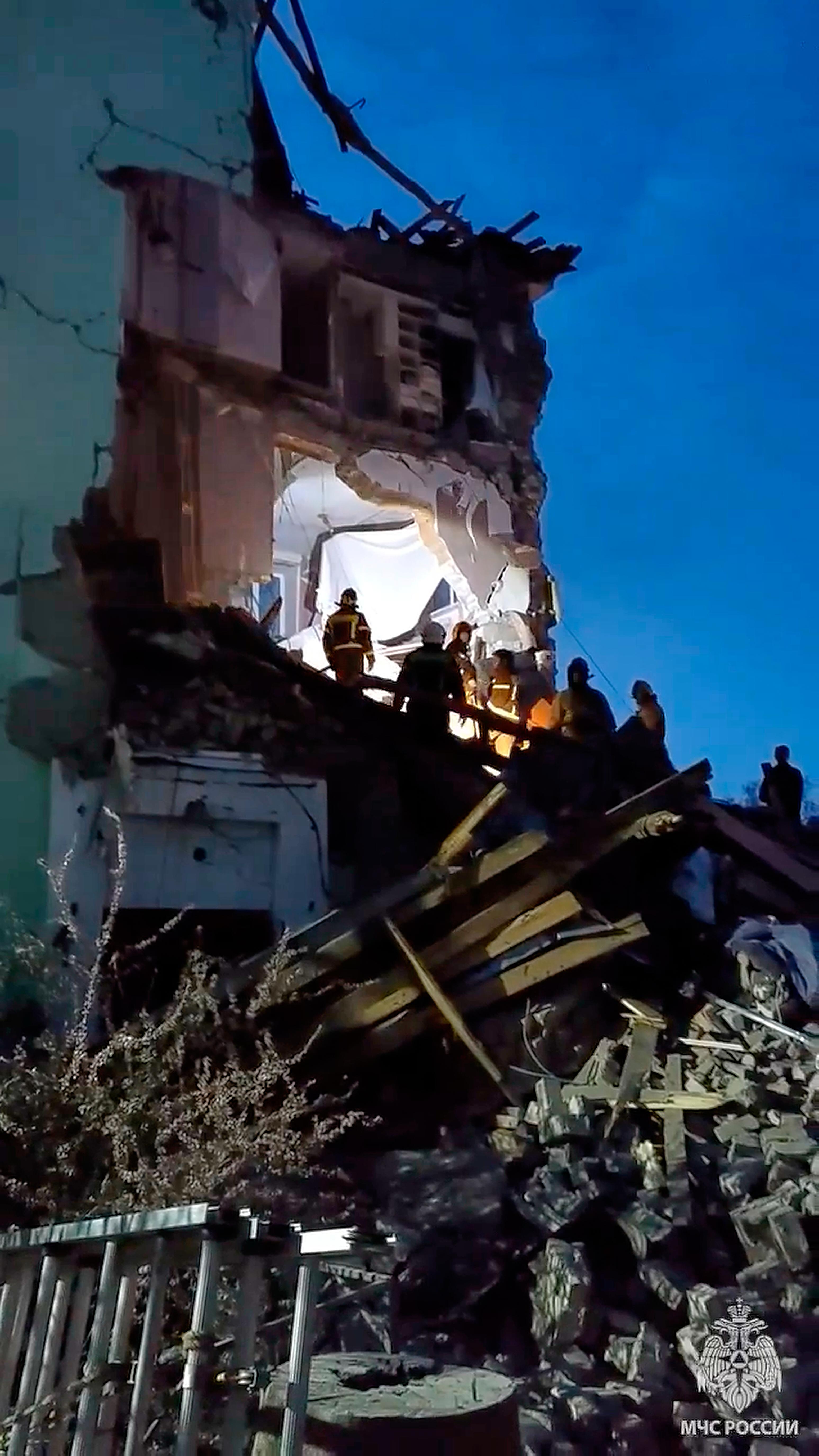 Russian Emergency Ministry employees work at the side of the damaged multi-story apartment building