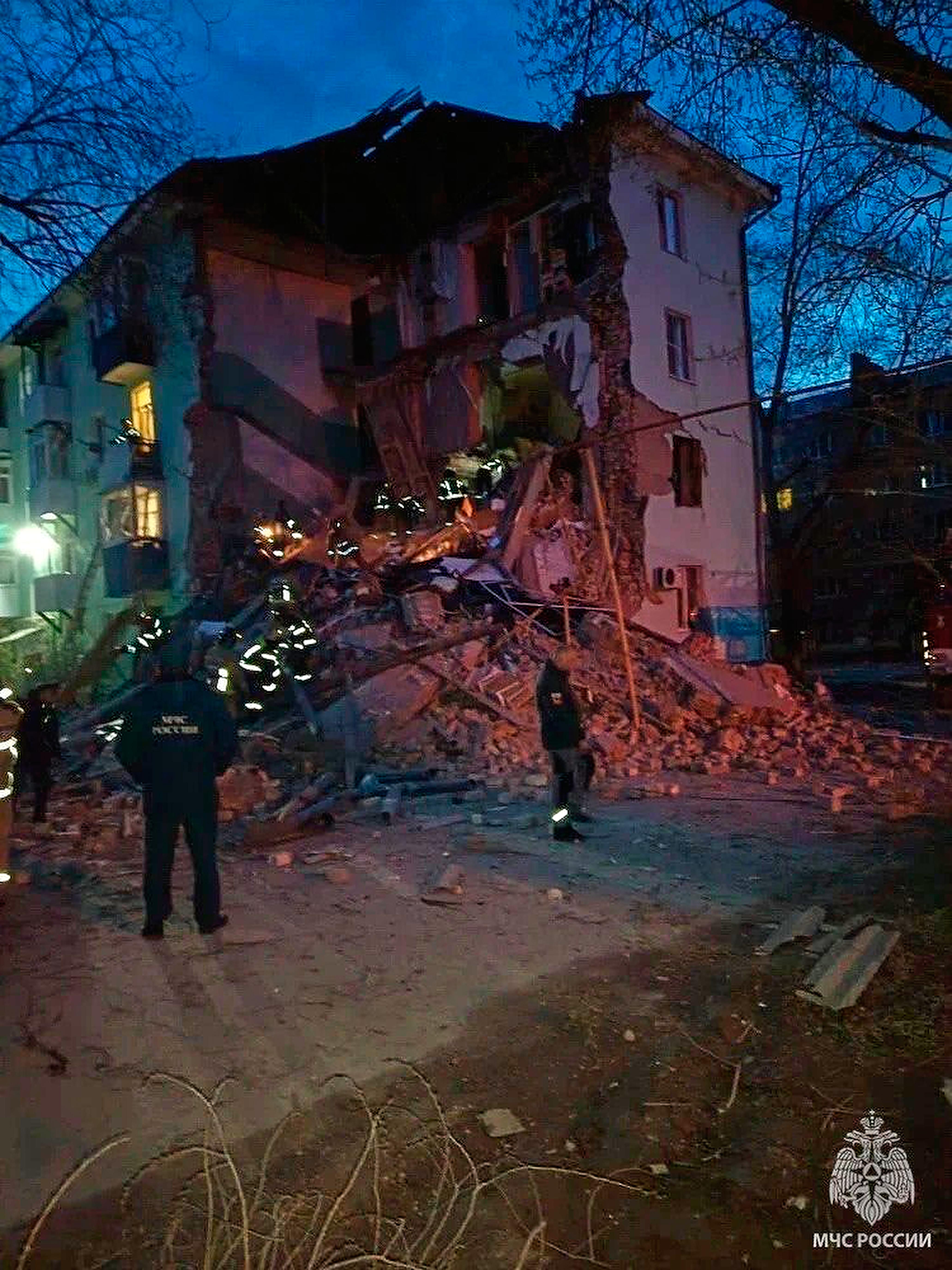 Russian Emergency Ministry employees work at the side of the damaged multi-story apartment building