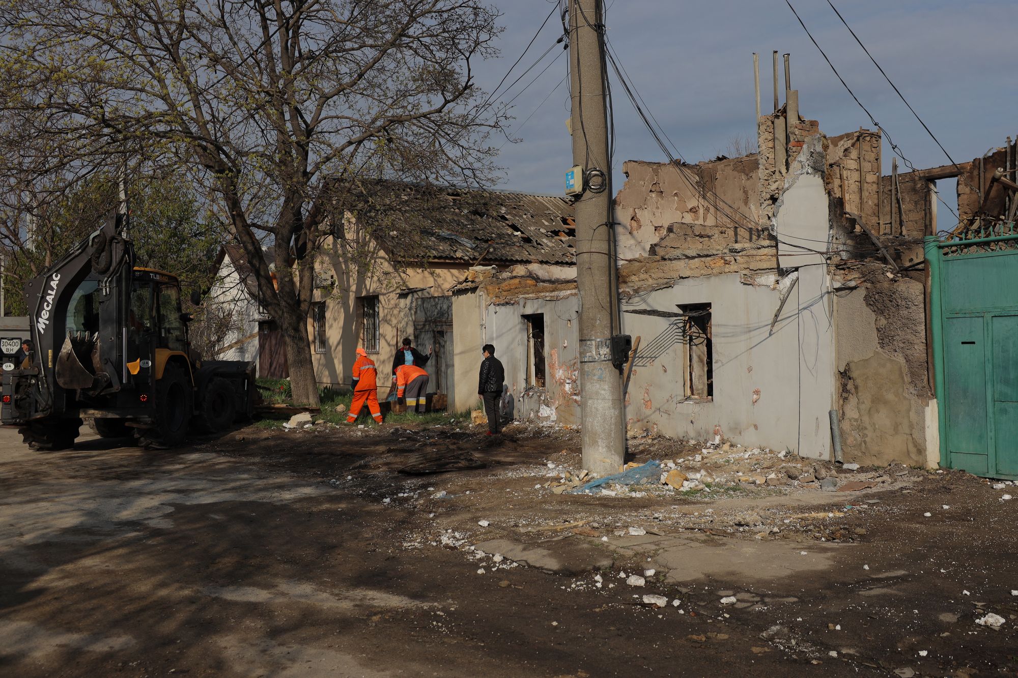 Communal workers clean debris next to a destroyed house following an air attack in Odesa