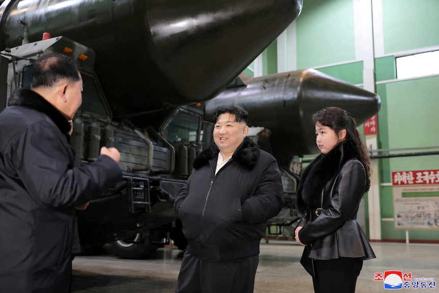 A man and woman stand in front of a tank.