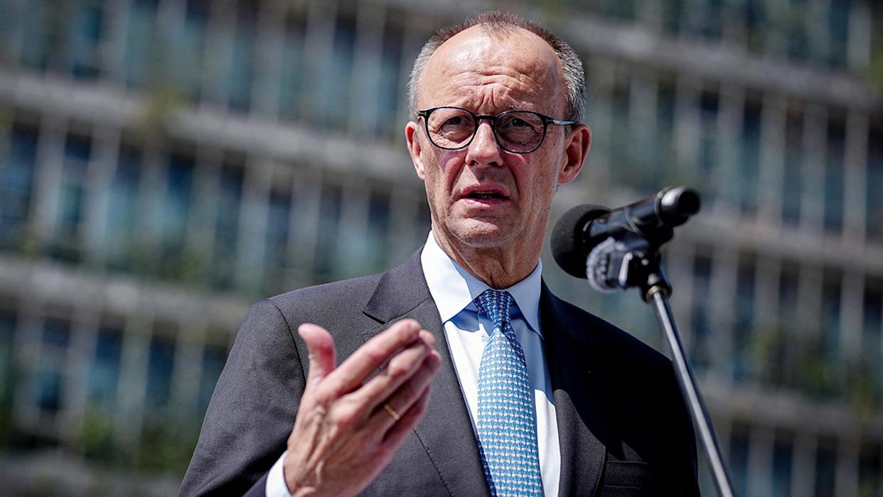 German Chancellor Friedrich Merz speaking at a podium during a trip to India