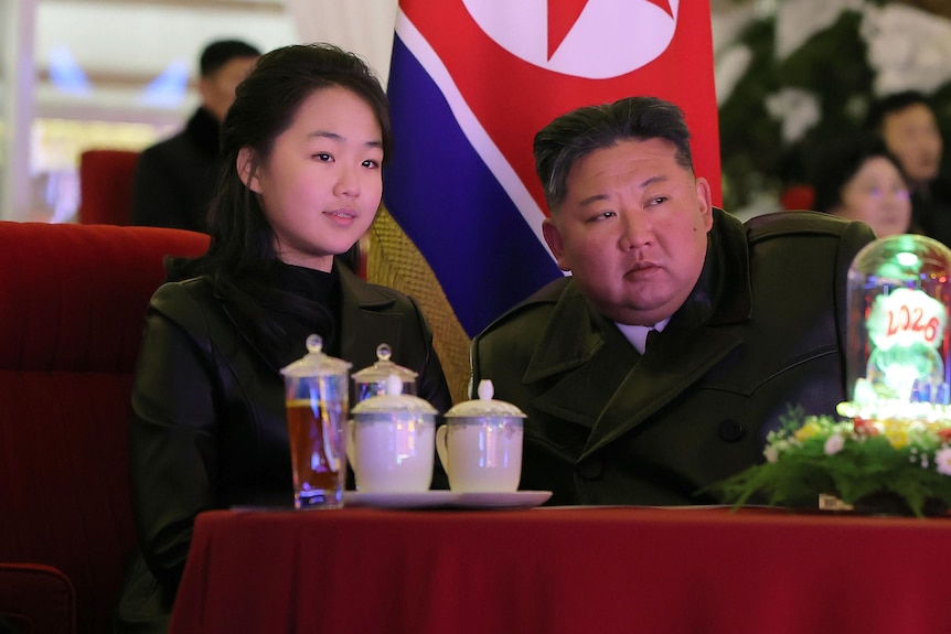 A man, woman and teenage girl sit as they watch a performance. 