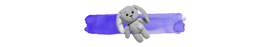 knitted soft toy in black and white on top of a wash of purple colour