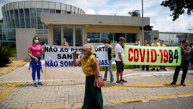 People hold signs during a protest against COVID-19 vaccine passports and mandatory COVID-19 vaccinations in Brazil.