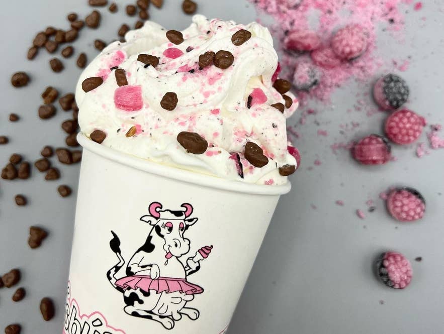 Mix-in ice cream from Ísbúð Huppu with chocolate pieces and berries in a branded cup on a light gray background Mix-in ice cream from Ísbúð Huppu with chocolate pieces and berries in a branded cup on a light gray background
