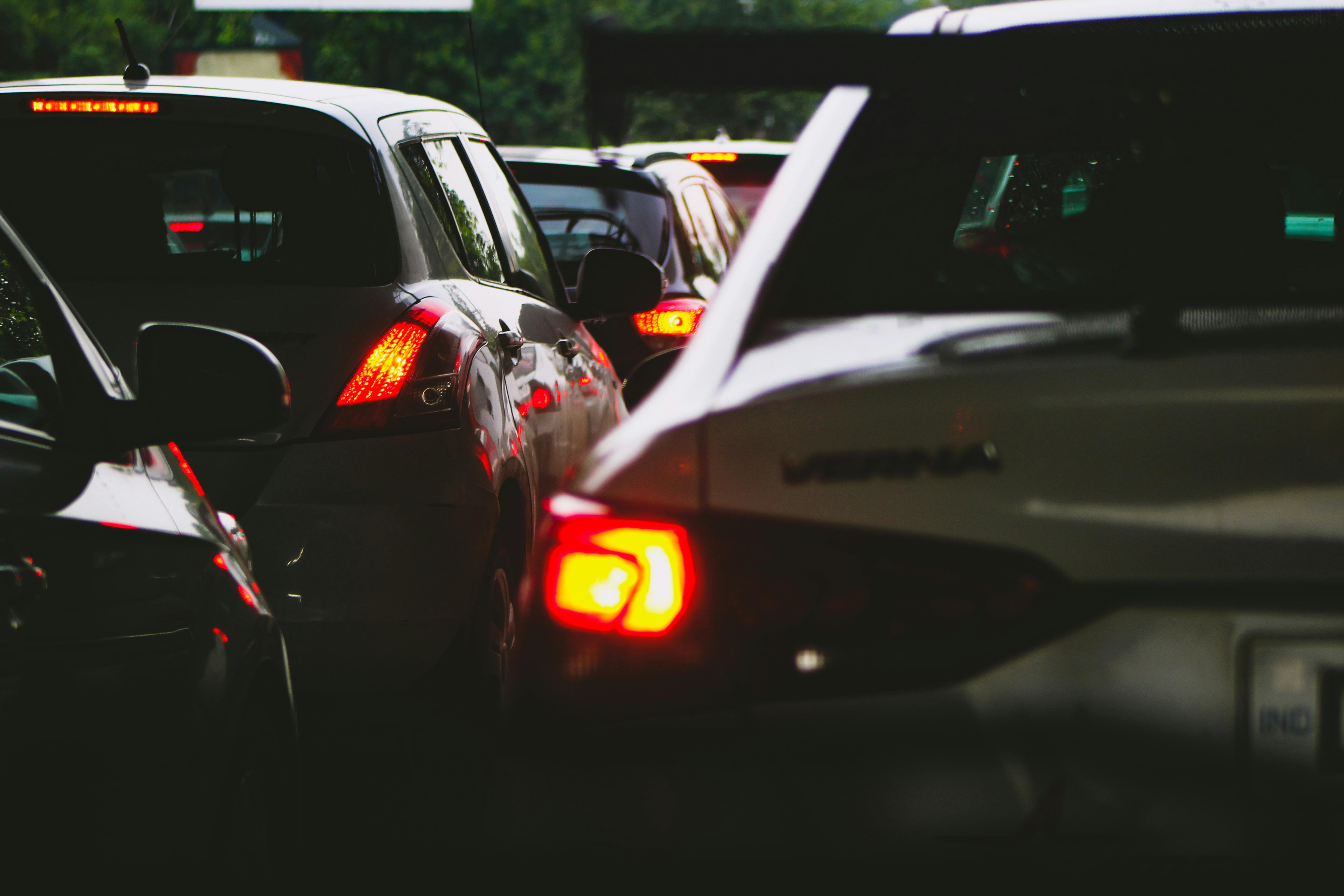 Cars in heavy traffic with brake lights glowing on a road, indicating congestion