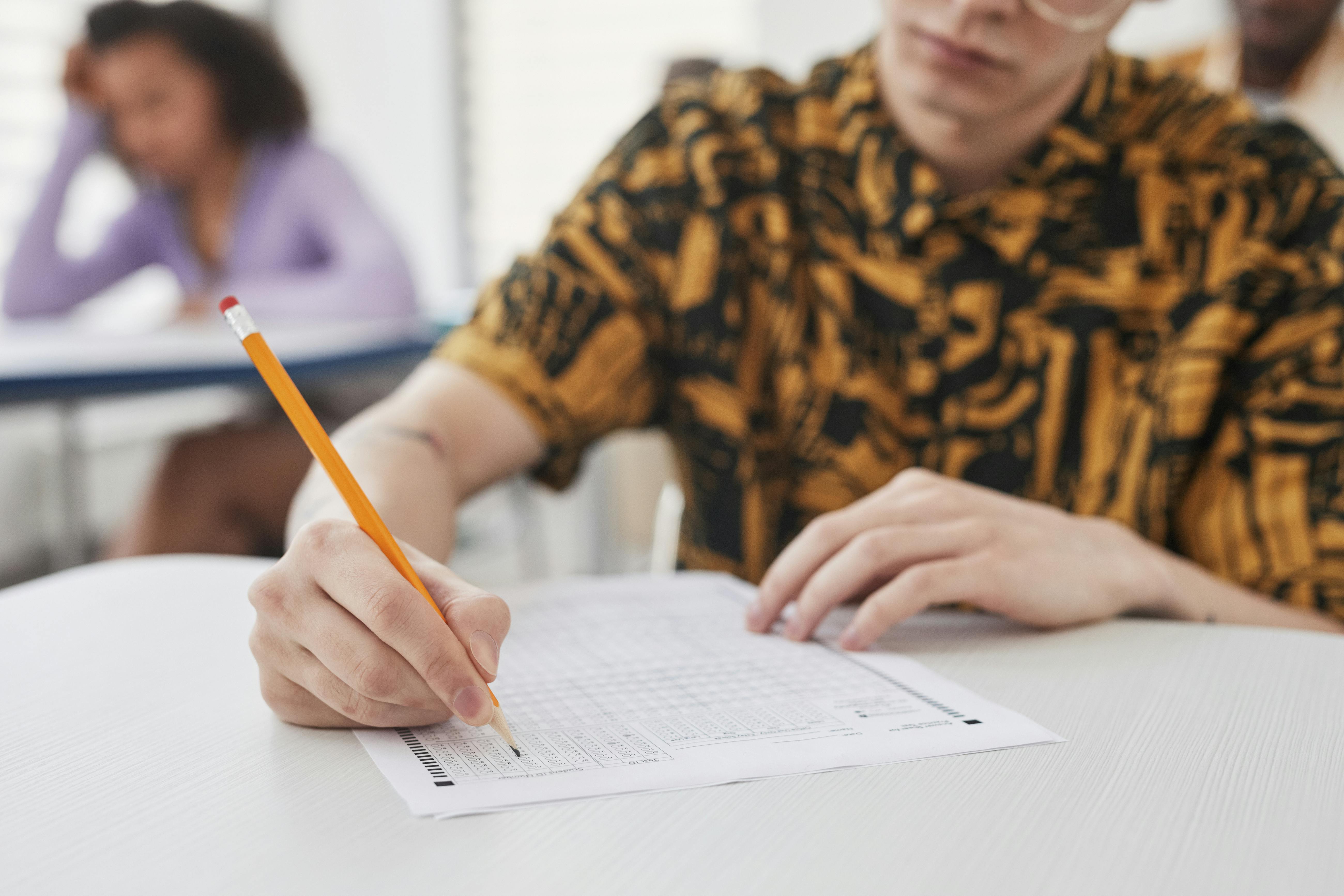 Student fills in a multiple-choice answer sheet with a pencil in a classroom
