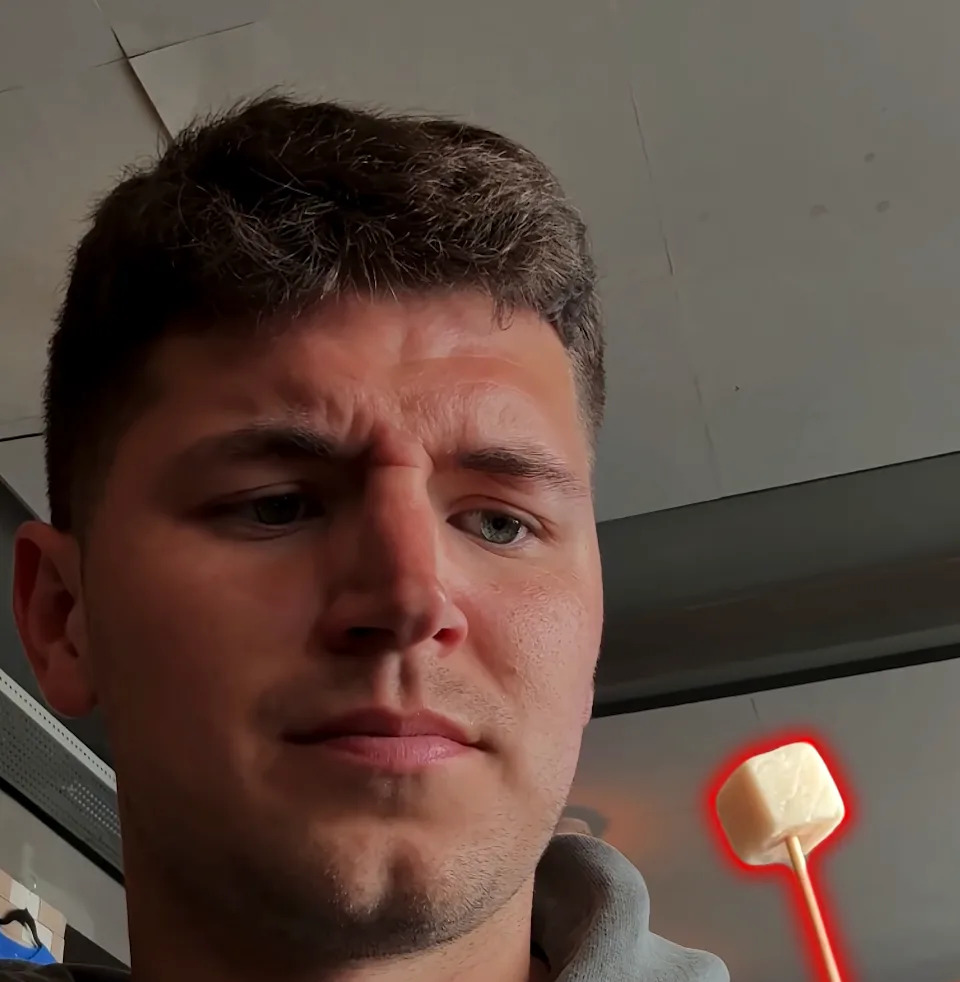 Nick DiGiovanni holding a piece of fermented shark on a toothpick.