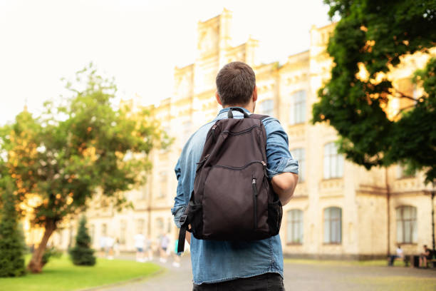 Student with a backpack walking toward a university building on a sunny day