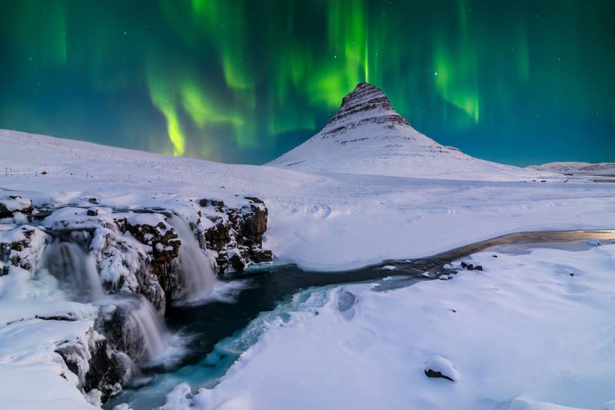 Northern lights over Kirkjufell mountain in West Iceland, capturing the icy winter scenes that gave Iceland its name