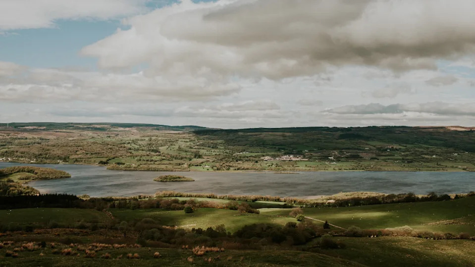 A rural landscape in County Fermanagh. Green fields and trees surround Lough Erne. 