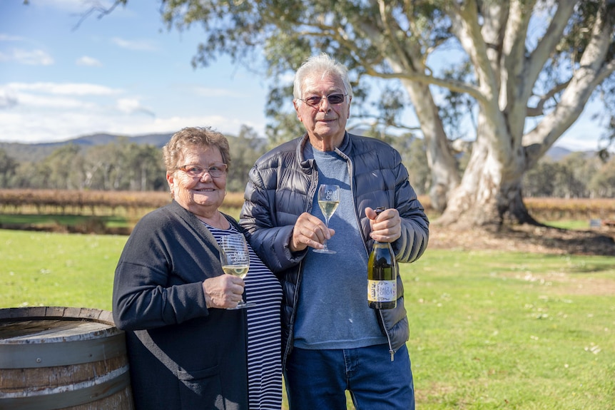 A woman and a man hold a glass of sparkling white wine