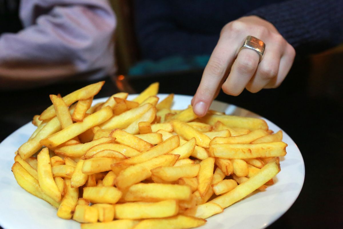 Hands of person eating from a plate of chips