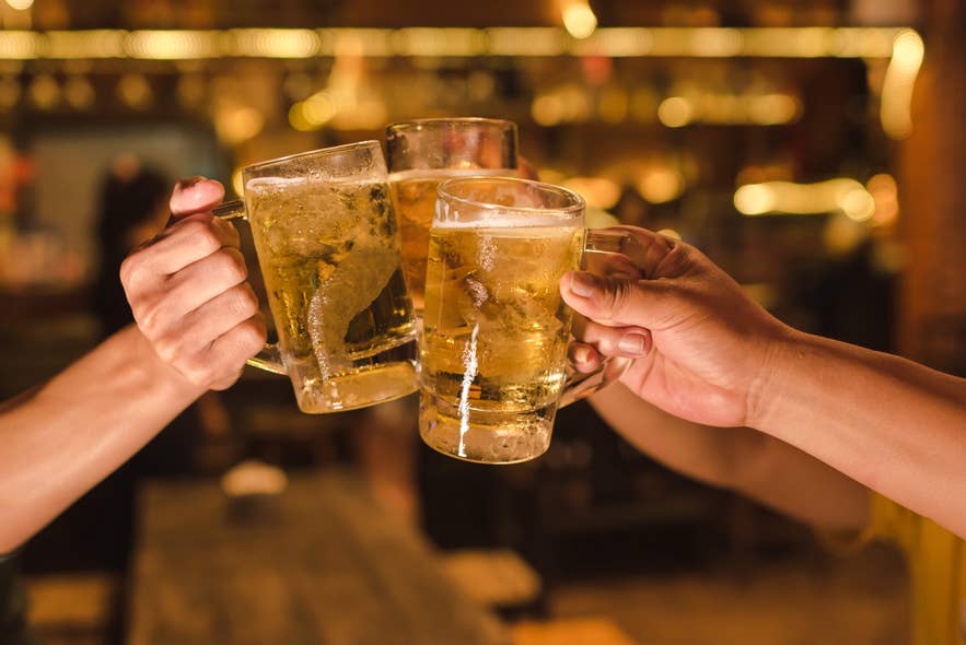 Friends toasting with cold beer mugs at a cozy bar, one of the fun ways to unwind while vacationing in Iceland. Friends toasting with cold beer mugs at a cozy bar, one of the fun ways to unwind while vacationing in Iceland.