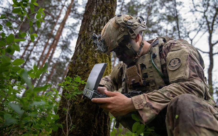 A U.S. Army infantryman operates a drone overhead from a remote control device.