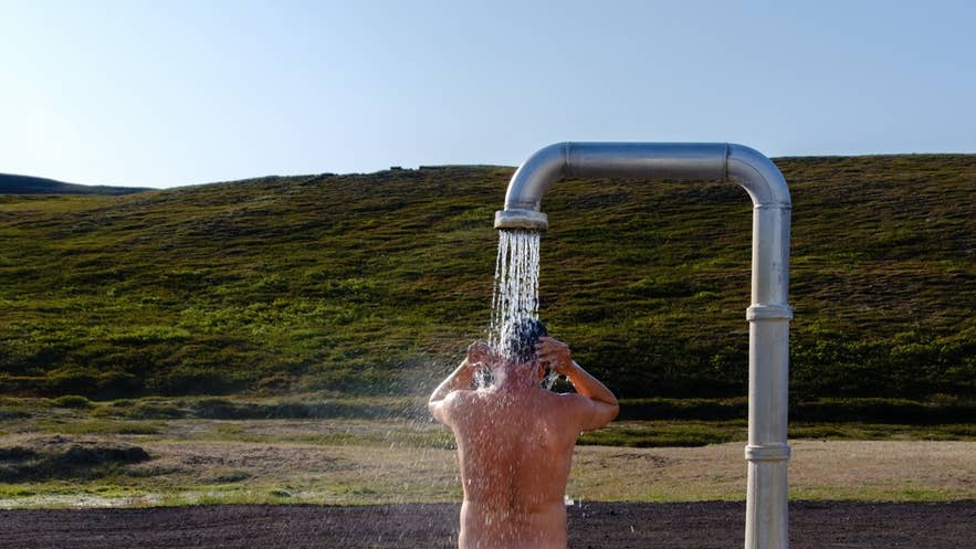 Icelander showering outdoors before entering a geothermal hot spring, following Iceland’s bathing etiquette. Icelander showering outdoors before entering a geothermal hot spring, following Iceland’s bathing etiquette.