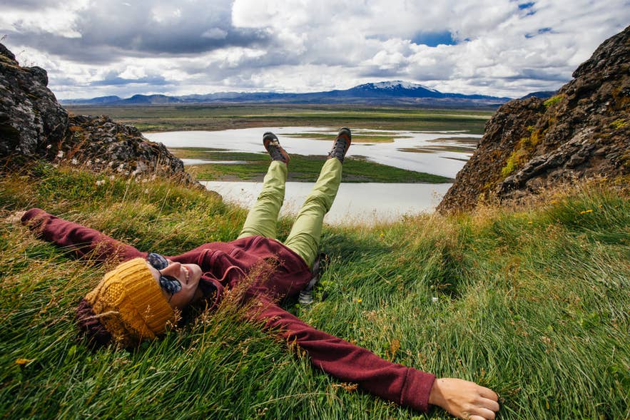 Icelander relaxing on grassy cliffs enjoying scenic views of rivers and mountains in North Iceland. Icelander relaxing on grassy cliffs enjoying scenic views of rivers and mountains in North Iceland.