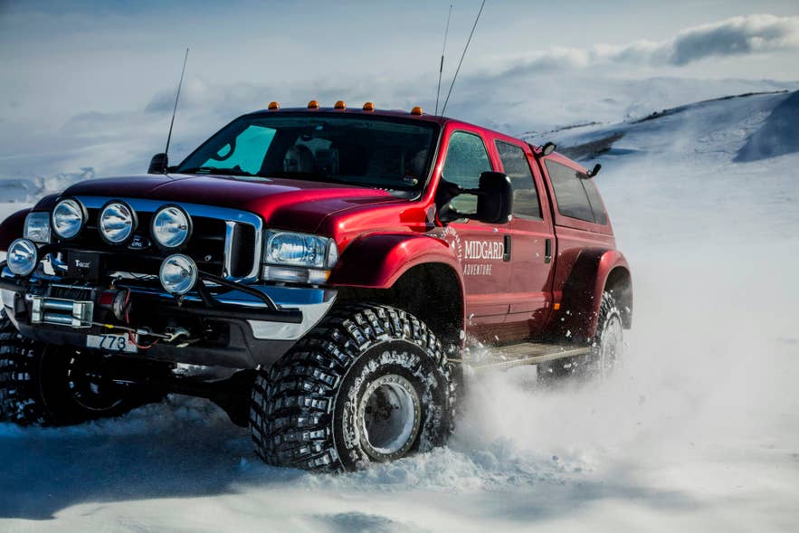 Icelander driving a red super jeep across snowy terrain in Iceland’s Highlands during a winter adventure. Icelander driving a red super jeep across snowy terrain in Iceland’s Highlands during a winter adventure.