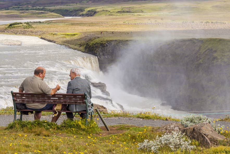 Icelanders sitting on a bench enjoying the view of Gullfoss Waterfall in Iceland’s Golden Circle. Icelanders sitting on a bench enjoying the view of Gullfoss Waterfall in Iceland’s Golden Circle.